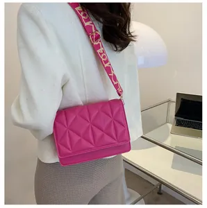 Detail of rose pink quilted crossbody bag with a wide graphic letter print shoulder strap