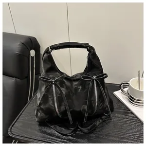 Detail der schwarzen Hobo-Tasche mit dekorativen Reißverschlüssen und Schleifenakzenten