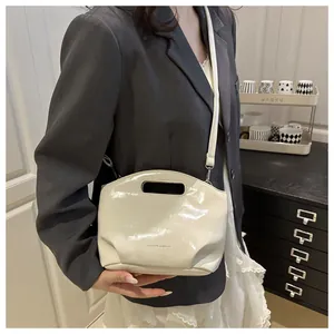 Detail of white glossy shoulder bag with top cutout handle and fashion text branding