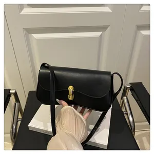 Detail shot of a black glossy leather underarm bag featuring a golden oval metal lock