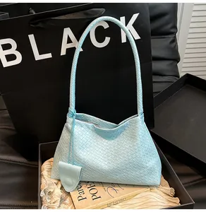 Detail view of light blue woven texture and matching teardrop charm on fashion bucket bag