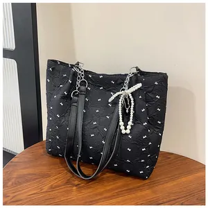 Detail of quilted tote bag with white bows, pearl charm, and silver chain strap