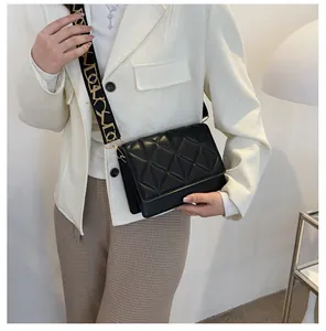 Close-up of quilted crossbody bag with wide woven strap and gold metal clasp