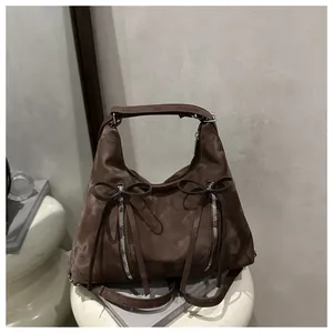 Detailansicht einer braunen Hobo-Tasche mit Schleifen und silbernen Reißverschlüssen