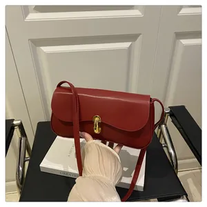 Close-up of a dark red leather shoulder bag with a minimalist gold metal clasp detail