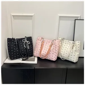 Detailed view of tote bags with bow-knot texture, metal chains and pearl bow pendants
