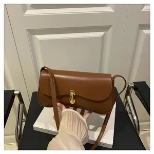 Detail view of a brown leather shoulder bag with a gold metal twist lock and smooth texture