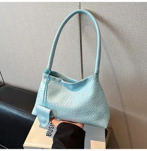 Detail of baby blue woven bucket bag with heart charm and thin braided top handle
