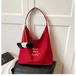 Detailed view of red canvas tote with yellow embroidery and premium leather straps