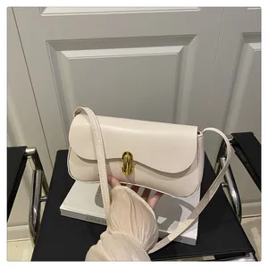 Detail of creamy white leather baguette bag with a cylindrical gold metal buckle closure