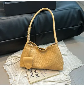Detail of yellow woven leather bucket bag featuring a small round hanging coin pouch