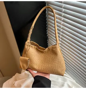 Detail of woven bucket bag in tan faux leather featuring elegant ruched handle design