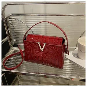 Detail of red croc-embossed leather handbag featuring a silver V-logo metal clasp
