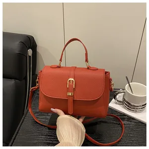 Detail of orange lychee grain leather handbag with gold buckles and adjustable strap
