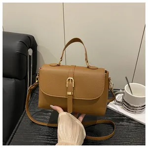 Close-up of brown litchi pattern leather bag with gold buckle and adjustable strap