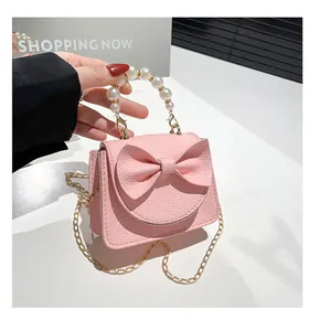 Detail of mini pink bow handbag with white pearl handle and gold chain strap