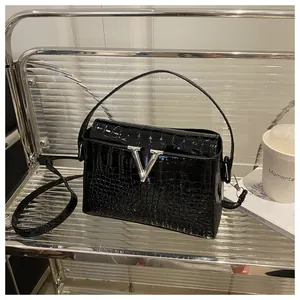 Detailed view of black crocodile pattern texture and silver V-shaped metal buckle on handbag