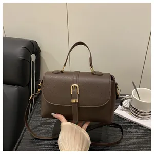 Detail of dark brown litchi pattern leather handbag with golden buckle hardware