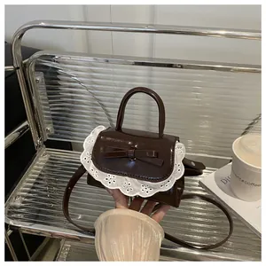 Detail of dark brown mini bag featuring white lace trim and bow on a transparent chair