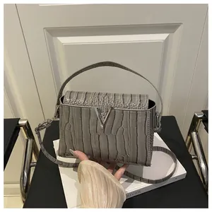 Detail of grey crocodile embossed handbag with luxury silver metal V-shaped buckle lock