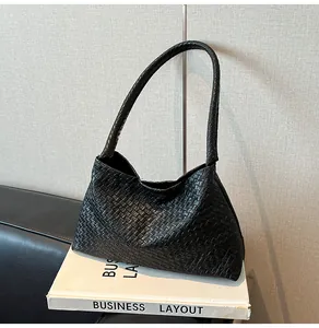 Detail of classic black woven hobo bag with intricate checkered pattern on white book