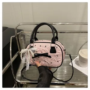 Detail of pink wrinkled texture Boston bag with black bow and pearl lace pendant charm