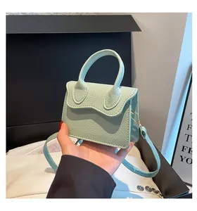 Close-up of mint green mini PU leather bag with lychee texture and wavy flap design