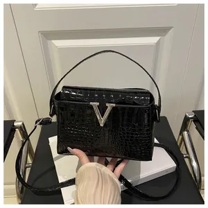 Detailed top view of black crocodile texture handbag with silver V metal buckle on book