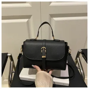 Detail of lychee pattern leather handbag with gold horseshoe buckle and top handle