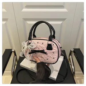Detailed close-up of pink textured handbag with black bows and pearl lace charm