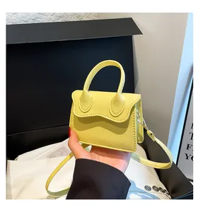 Detail shot of bright yellow lychee grain leather mini bag with a wave flap and strap