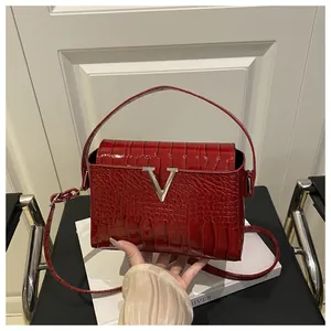 Detail of red croc-effect patent leather handbag with silver V-shaped metal buckle