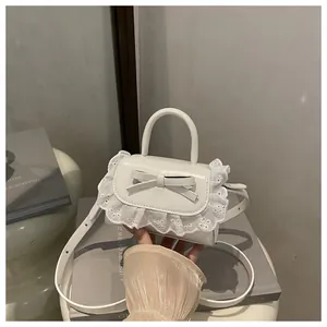 Detail of white mini bow handbag with delicate lace edges and glossy synthetic leather
