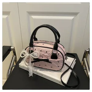 Close-up of pink textured bowling bag with black bows and pearl lace pendant