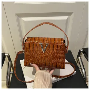 Detail of caramel brown crocodile embossed leather with silver V-shaped metal buckle