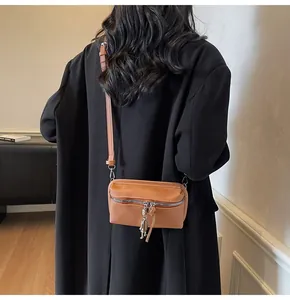 Detail of ginger rectangular crossbody bag with astronaut charm on a black coat