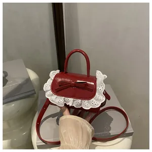 Detail of red patent leather mini bag with 3D bow and white lace trim detail