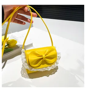 Detail view of mini yellow crossbody bag with large bow and delicate white lace trim