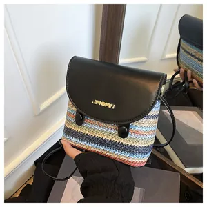 Detail of colorful straw woven bucket bag with black leather flap and metal logo