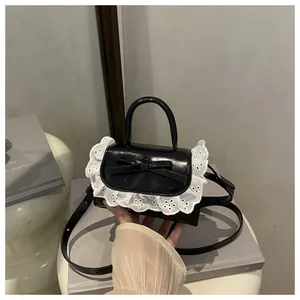 Detail of black bow handbag with white lace trim and adjustable shoulder strap