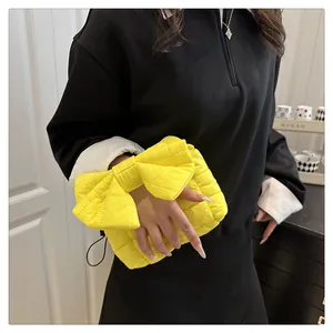 Detail of bright yellow quilted bow handbag with textured fabric and hand-held design