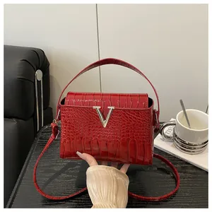 Detail of red crocodile texture handbag featuring a silver V-shaped metal buckle accent