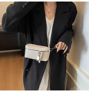 Detail of a white leather square bag with silver zipper and charm on a black coat