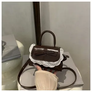 Detail of dark brown leather mini bag with lace trim and sweet bow knot decoration