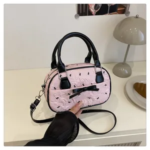Detail of pink pleated mini bowling bag with black bow print and leather handles