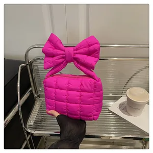 Macro shot of rose red quilted puffer handbag with large stylish bow top handle