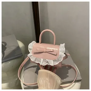 Close-up of pink patent leather mini bag featuring bow detail and white lace trim edge