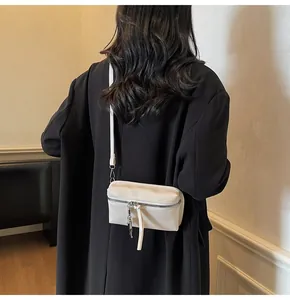 Detail of minimalist white square crossbody bag with silver zipper and long pullers