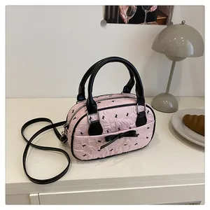 Detail of pink quilted bowling bag with black bow prints on a cozy home table setting
