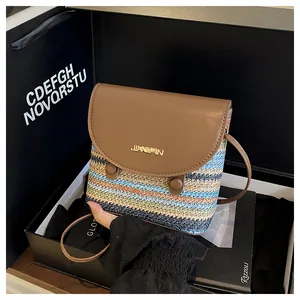 Detail of colorful woven bucket bag with brown leather flap and golden logo accent